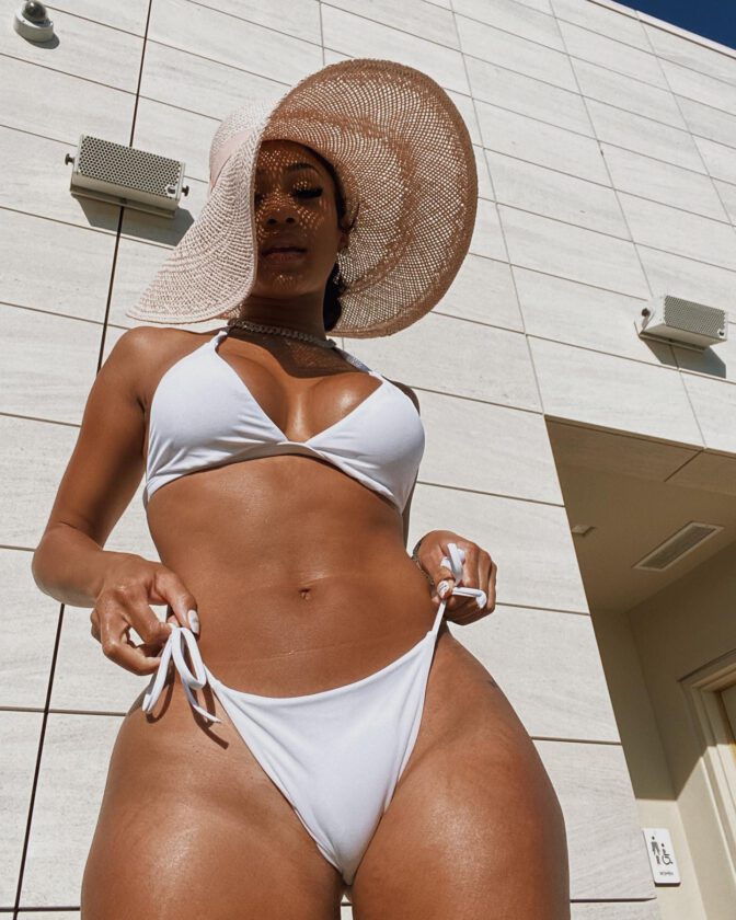 Saweetie Posing In A White Bikini, Showcasing Her Curvy Body And Big Boobs.